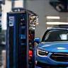 Technician performing hybrid car service in shop